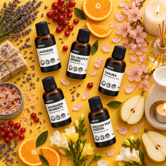 Five small bottles of fragrance oil aligned in a row on a white surface, each labeled with different fragrance names such as Red Fruits & Berries, Mandarin Moments, Sakura, English Pear & Freesia, and Lavender.